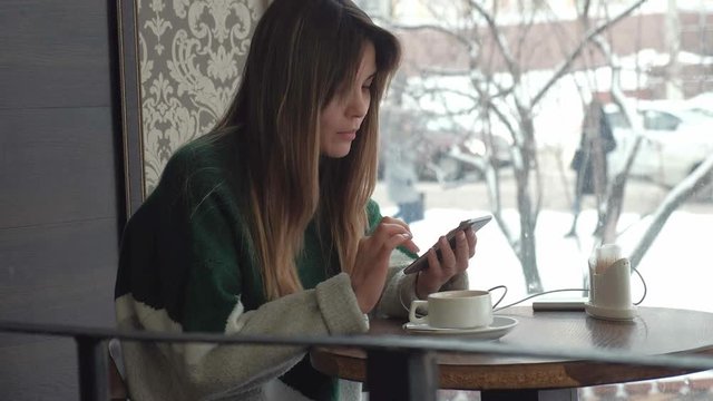 Woman texting, sending sms on smartphone in cafe