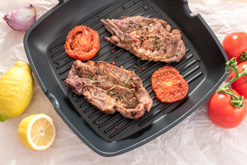 Grilled steak on grill pan with tomatoes and lemon on white background