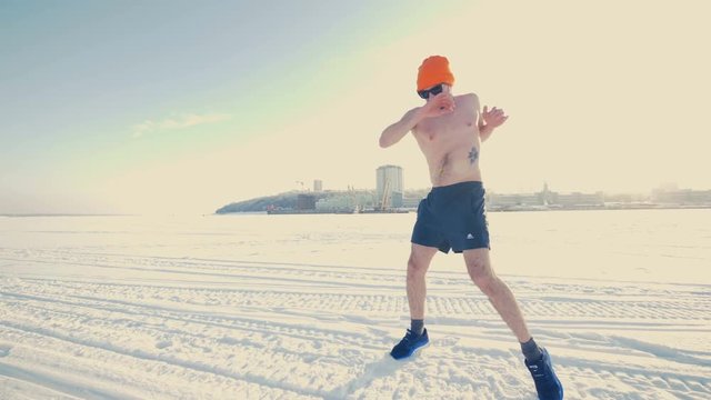 A man performs stretching exercises in the winter. 