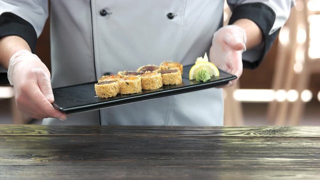Chef holding a sushi plate. Breaded unagi maki with sauce.