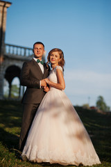 Naklejka premium Fabulous wedding couple posing in front of an old medieval castle in the countryside on a sunny day.