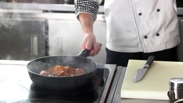 Chef frying chicken wings. Meat being cooked.