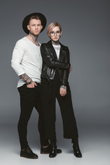 fashionable tattooed couple posing together, isolated on grey