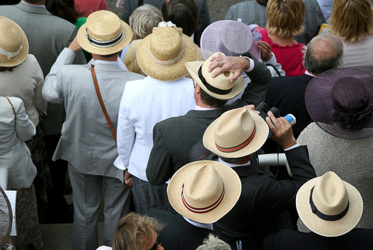 Overhead image of people watching a horse race, in panama hats 