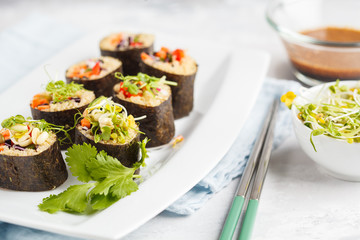 Vegan sushi rolls with quinoa, vegetables and soy-nut sauce on a white plate, light background. Vegan Healthy Food Concept.
