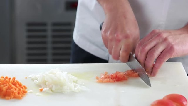 Hands chopping tomato. Man cutting vegetable close up.