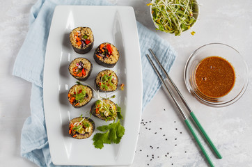 Vegan sushi rolls with quinoa, vegetables and soy-nut sauce on a white plate, light background. Top view. Vegan Healthy Food Concept.
