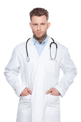 professional doctor with stethoscope and hands in pockets of white coat, isolated on white
