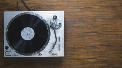 over the head view of the hand starting the turntable and playing vinyl record.