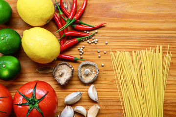 pasta ingredients on wooden table in kitchen, spaghetti,tomato,garlic,mushroom,line,lemon, chilli, pepper on cutting board