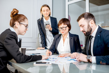 Business people working with charts and documents sitting at the table during the conference in the office