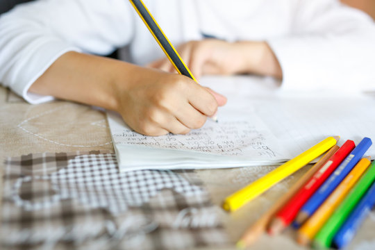 Child Doing Homework And Writing Story Essay. Elementary Or Primary School Class. Closeup Of Hands And Colorful Pencils