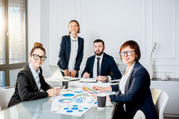 Portrait of a business people working with charts and documents sitting at the table during the conference in the office