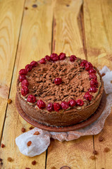 Carob tart with cherries ans raisins on the wooden background. Powdered carob pie with cherries. General view