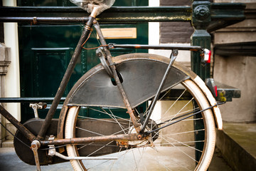 Detail of vintage old rusty bicycle parked in front of dutch house with typical architecture of Amsterdam, Netherlands.