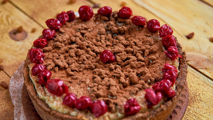 Carob tart with cherries ans raisins on the wooden background. Powdered carob pie with cherries. Close up view