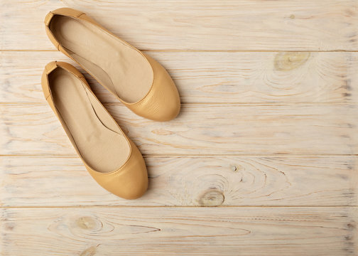 Fashion trend - women's shoes golden pearl color on a wooden background.