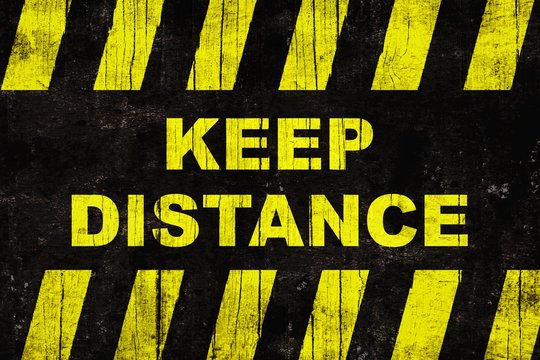 Grungy "keep distance" text warning sign with yellow and black stripes painted over cracked wood.