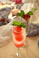 Sparkling cocktail with watermelon and melon ball-shaped pieces and ice and decorated with mint