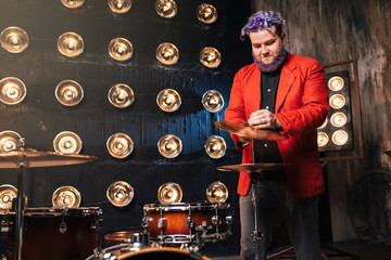 Fototapeta premium Bearded drummer in red suit on the stage