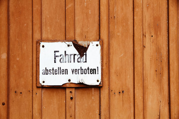 “Fahrrad abstellen verboten” (in German, parking of bicycles is prohibited) old vintage cracked sign fixed to a brown wooden door.