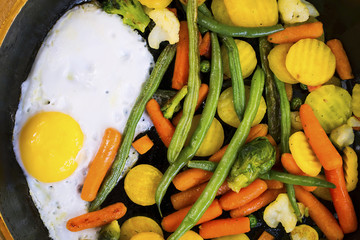 fried egg with vegetables in a frying pan