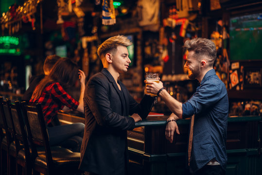 Men raised their glasses with beer in a sport pub