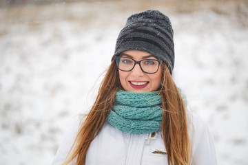 portrait of a cheerful girl with glasses in a snowfall in winter.