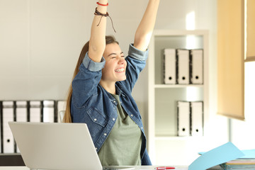 Satisfied intern raising arms at office - obrazy, fototapety, plakaty