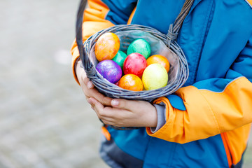 Close-up of hands of little child with colorful Easter eggs in basket