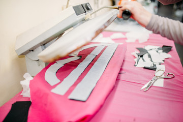 Clothes designer works on steam press