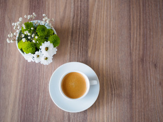Tasse Kaffee und eine weiße Vase mit Blumen 