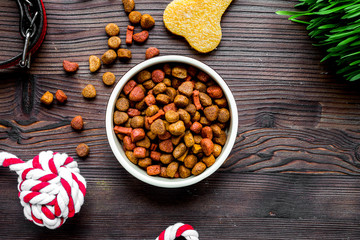 dry dog food in bowl on wooden background top view