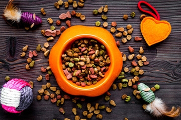 dry cat food in bowl on wooden background top view