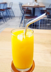 A tall glass of freshly squeezed orange juice with an environmentally friendly metal straw