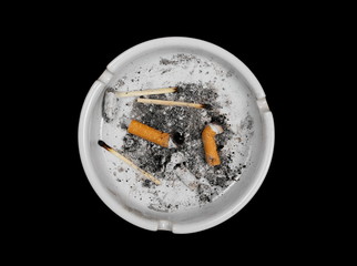 Cigarette stubs, matches and ash in ashtray isolated on white background, top view