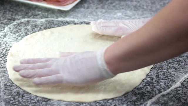 Thin pizza crust close up. Hands of chef preparing dough.