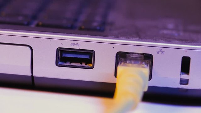 Closeup of Ethernet cable plug inserted into port on the side of a laptop