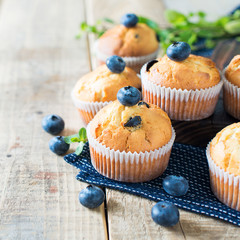 Blueberries muffins or cupcakes with mint leaves on wooden texture