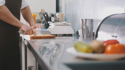 Male chef preparing salad in commercial kitchen - cuts the onion