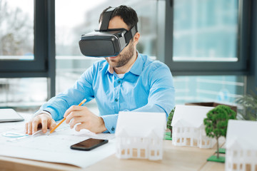 Thorough worker. Pleasant bristled engineer sitting at the desk in the office and working on the...