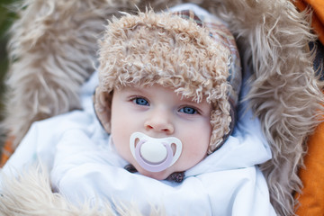 Little baby boy in warm winter clothes outdoor