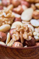 Mixed nuts including hazelnuts, walnuts, blanched almonds and cashews in wooden bowl