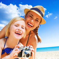 happy mother and child on seashore with retro photo camera