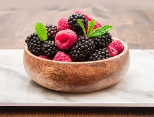 Wooden cup with fresh berries on wooden table 