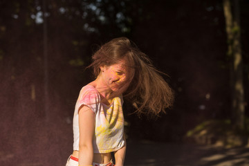 Expressive brunette woman having fun at Holi festival in the park