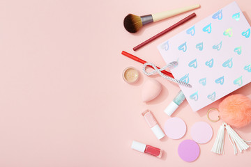 Makeup and gift bag flat lay on pink background, Valentine's Day beauty products