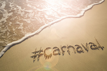 Fototapeta premium Modern message for Carnaval with a social media-friendly hashtag written on smooth sand beach