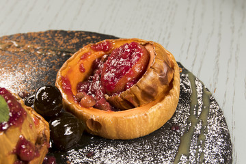 baked pumpkin with strawberries jam on wooden table