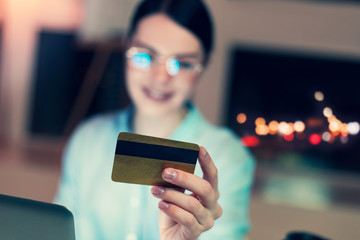 Convenient payment. The focus being on a golden credit card in the hands of a dark-haired young woman in eyeglasses reading the card number
